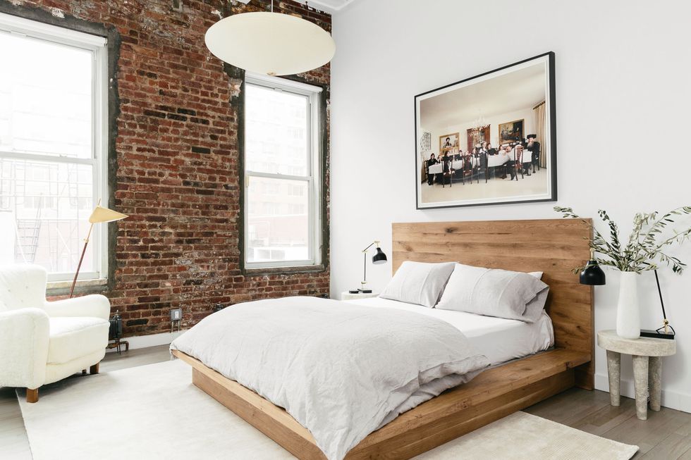 Chiếc giường từ gỗ tự nhiên kết hợp với tường gạch tạo vẻ mộc mạc, thân thiện cho căn phòng